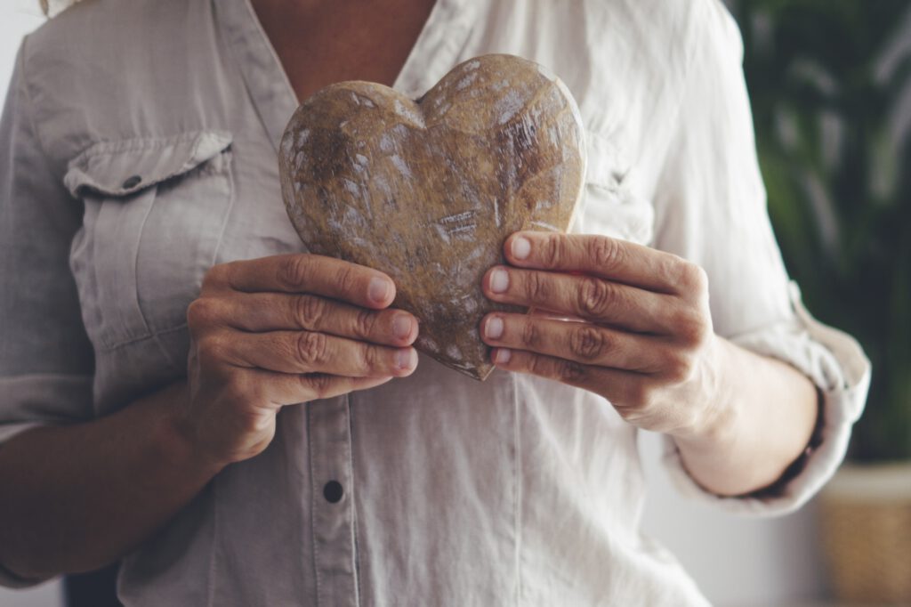 Close up of woman hands holding wooden heart. Concept of heart attack prevention and healthy